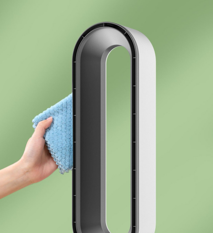 Hånd rengør moderne blæser uden vinger med blå klud, minimalistisk design, grøn baggrund. Innovativ teknologi, stilfuld indretning.