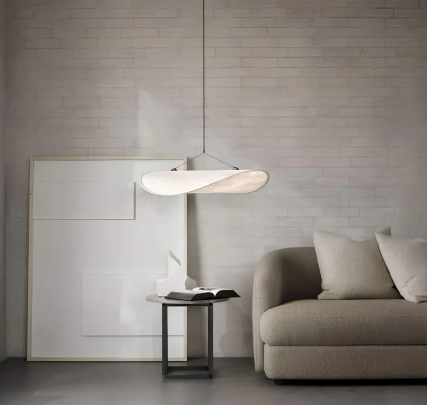 Moderne stueindretning med elegant sofa, minimalistisk kunst på væggen og stilfuld loftslampe. Skandinavisk design, lys og neutral farvepalet.