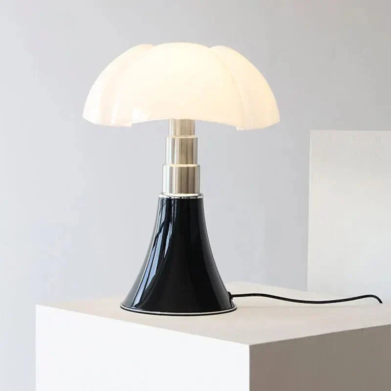 Sort og hvid bordlampe med svampeformet skærm på hvid piedestal, moderne design, indendørs belysning, stilfuld indretning, minimalistisk lampe.