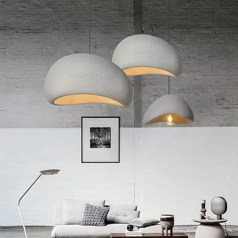 Moderne stue med tre store, hvide hængelamper, minimalistisk sofa, gulvlampe og kunst på væggen. Skandinavisk design, stilfuld indretning.