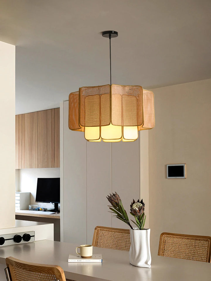 Moderne pendellampe i fletdesign hænger over spisebord i skandinavisk køkken. Naturlige materialer og minimalistisk indretning.