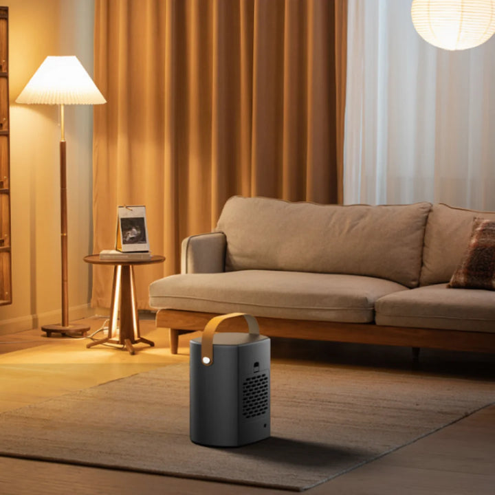 Stilfuld bærbar projektor i moderne stue med sofa, gulvlampe og tæppe. Perfekt til hjemmebiograf og underholdning.