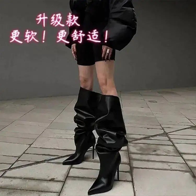 Person iført sorte, overdimensionerede støvler og sort tøj på grå flisebelagt gade. Moderne mode, unikke støvler, street style.