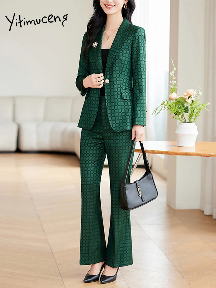 Kvinde i grønternet jakkesæt med sort taske og sorte sko, står i moderne stue. Elegant kontorlook, stilfuldt tøj til kvinder, mode 2023.
