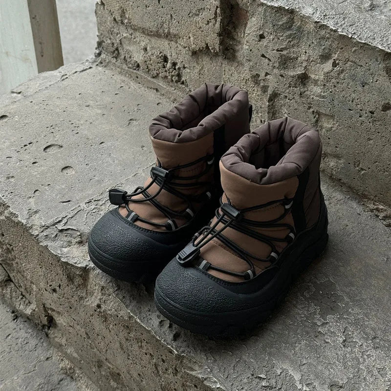 Brune vandrestøvler med sorte snørebånd på betonbaggrund. Komfortable, slidstærke sko til udendørsaktiviteter og trekking.