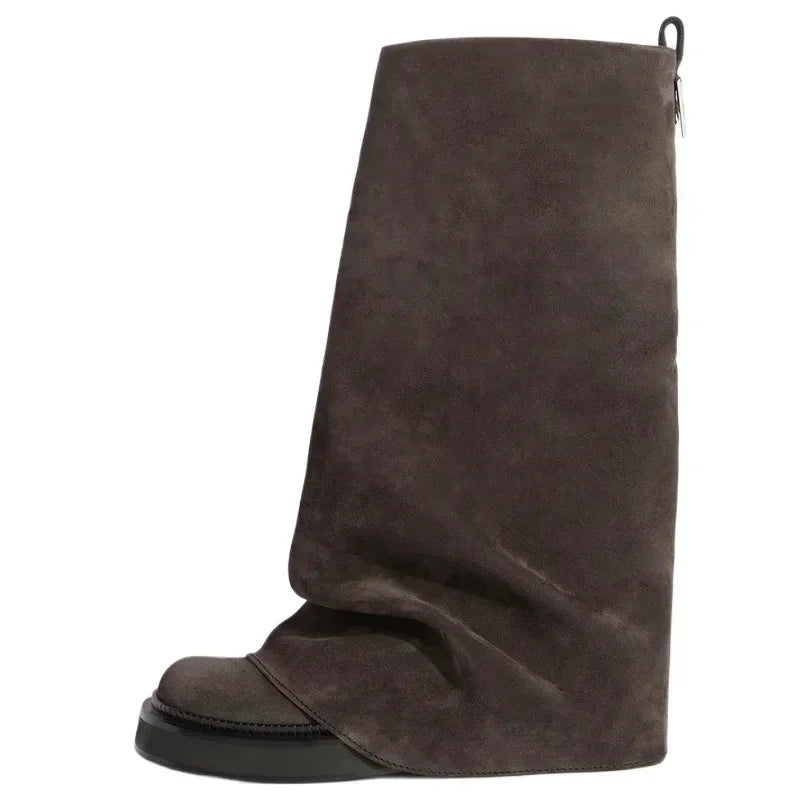 Brun ruskindsstøvle med unik, asymmetrisk design og sort sål. Moderne modefodtøj, stilfuld og trendy til efterår og vinter.
