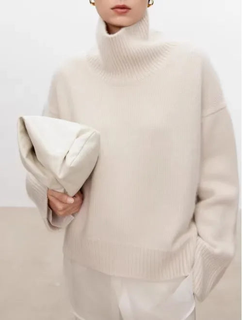 Kvinde i beige rullekrave sweater holder en matchende taske. Minimalistisk mode, elegant design, neutral farvepalet, moderne stil.