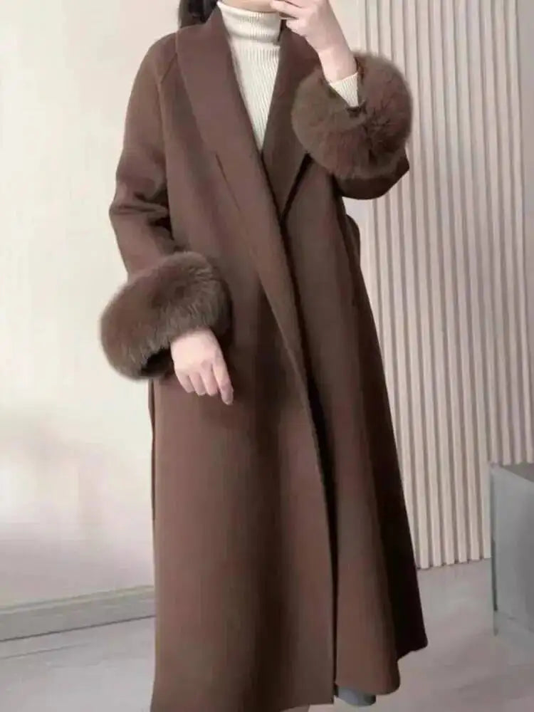 Brun frakke med pelsmanchetter, elegant vintermode, kvinde i stilfuldt overtøj, moderne design, varm og trendy beklædning til koldt vejr.