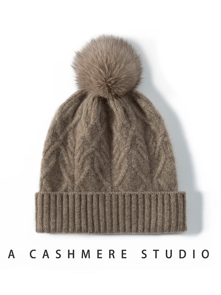 Brun kashmir hue med kabelstrik og pelskvast, stilfuldt vintertilbehør. Perfekt til varme og mode. A Cashmere Studio.