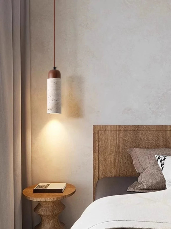 Hængelampe i beton over natbord i moderne soveværelse med træpaneler og grå sengetøj. Stilfuld belysning, minimalistisk indretning.