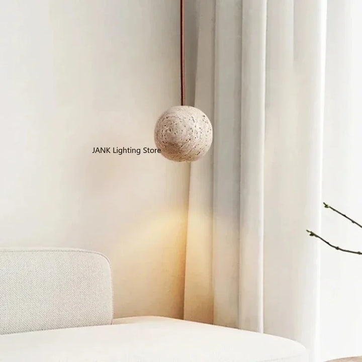 Moderne rund pendellampe i beton hænger i minimalistisk stue med hvid sofa og gardiner. Stilfuld belysning, skandinavisk design.