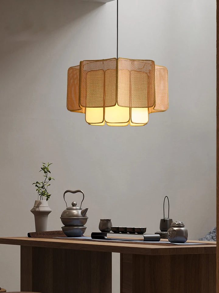 Moderne spisebord med asiatisk-inspireret te-sæt og elegant, gylden loftslampe. Minimalistisk indretning, varm belysning, stilfuldt design.