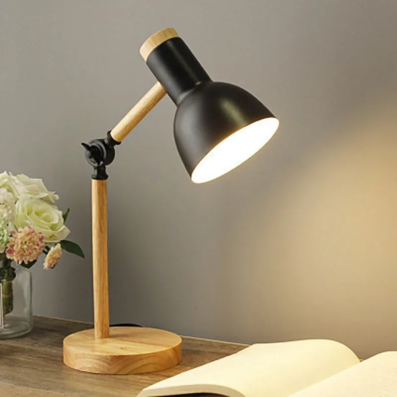 Sort skrivebordslampe i træ med justerbar arm, lyser op på en åben bog. Moderne design, ideel til kontor eller studie. Blomster i baggrunden.
