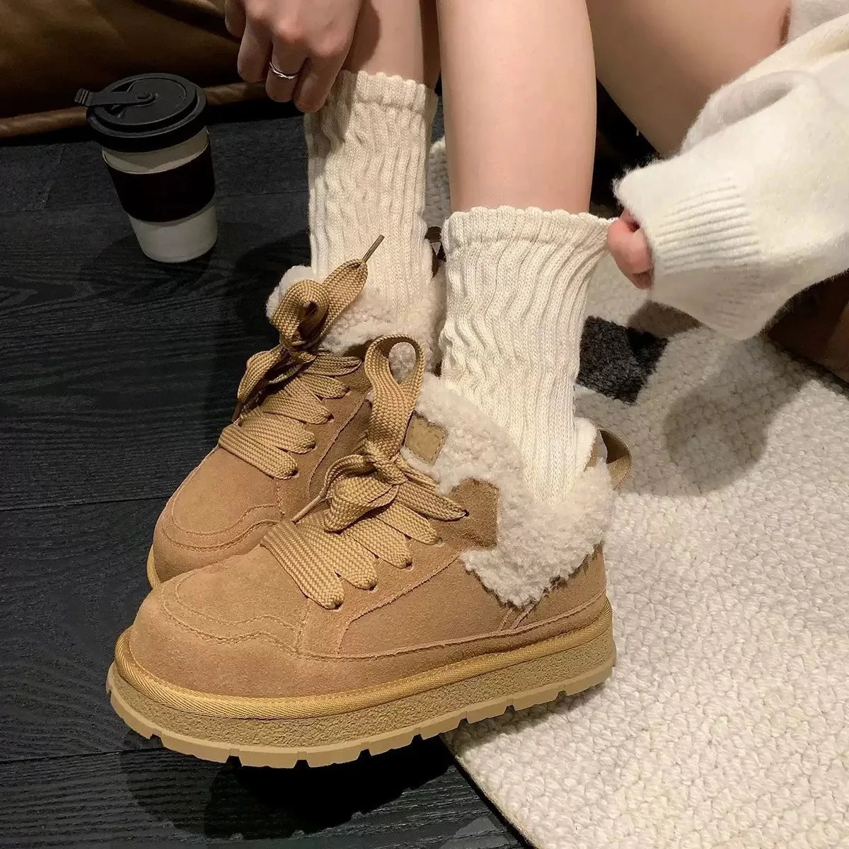 Brune vinterstøvler med hvidt fleecefor, tykke såler og snørebånd. Båret med hvide, strikkede sokker. Perfekt til vintermode og komfort.