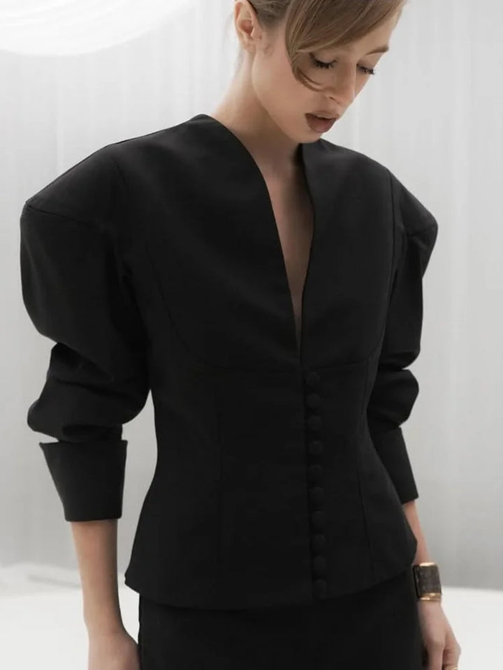 Kvinde i elegant sort kjole med pufærmer og dyb V-udskæring, moderne mode, minimalistisk design, stilfuldt look, sort tøj, fashionabelt outfit.