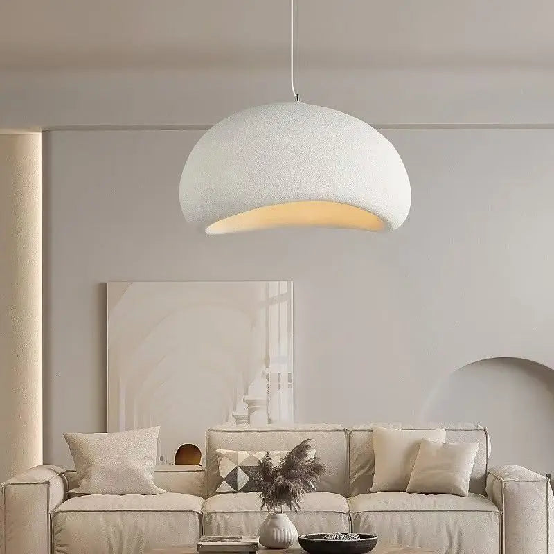 Moderne hvid pendellampe i minimalistisk stueindretning med beige sofa og puder. Stilfuld belysning, skandinavisk design, hjemmedekoration.
