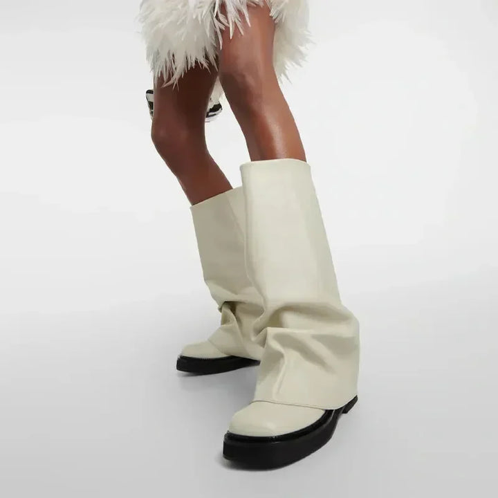 Hvide, oversized støvler med sort sål på model i fjerkjole. Moderne mode, unikt fodtøj, trendy design, stilfuldt look.