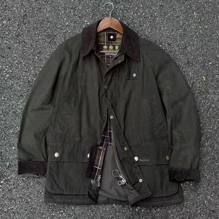 Mørkegrøn jakke med brun krave og ternet for, hængende på bøjle. Perfekt til udendørs brug, stilfuld og funktionel.