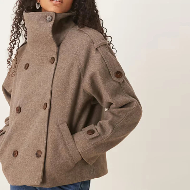Kvinde iført stilfuld brun uldjakke med knapper, høj krave og lommer. Perfekt til efterårsmode og udendørs brug.