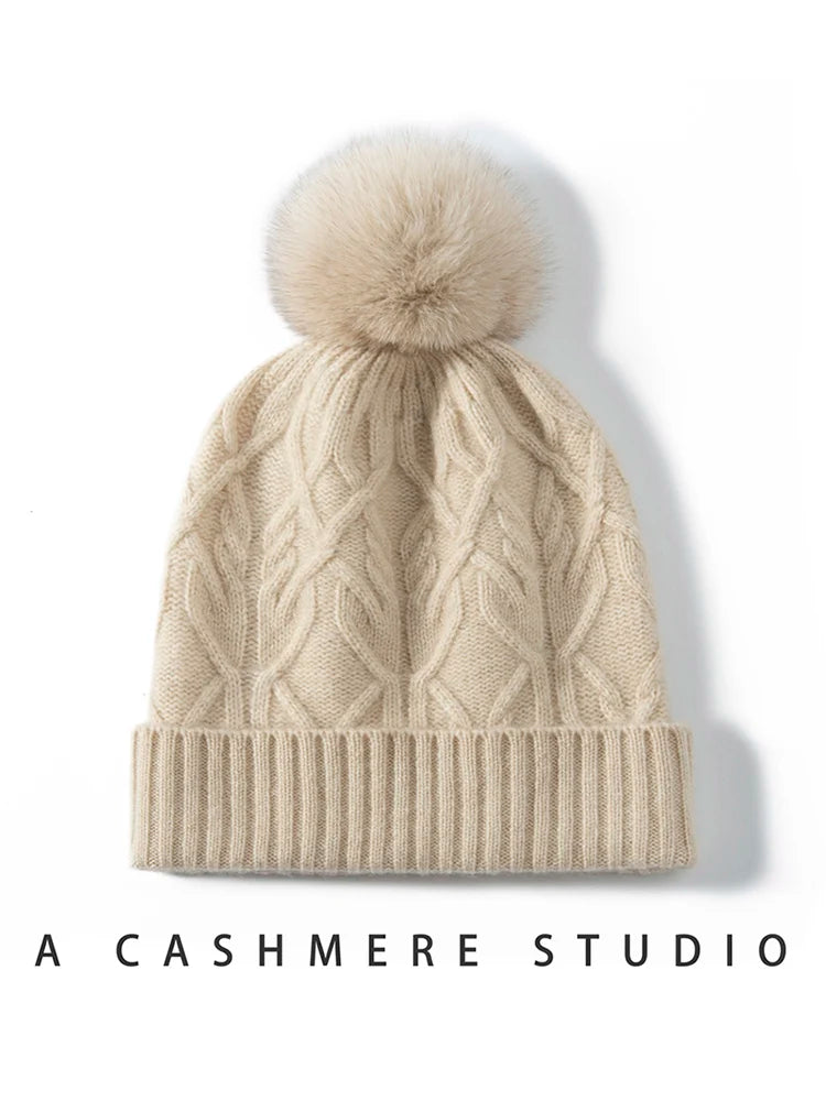 Beige kashmirhue med kabelstrik og pompon, elegant vintertilbehør, varm og stilfuld, perfekt til kolde dage.