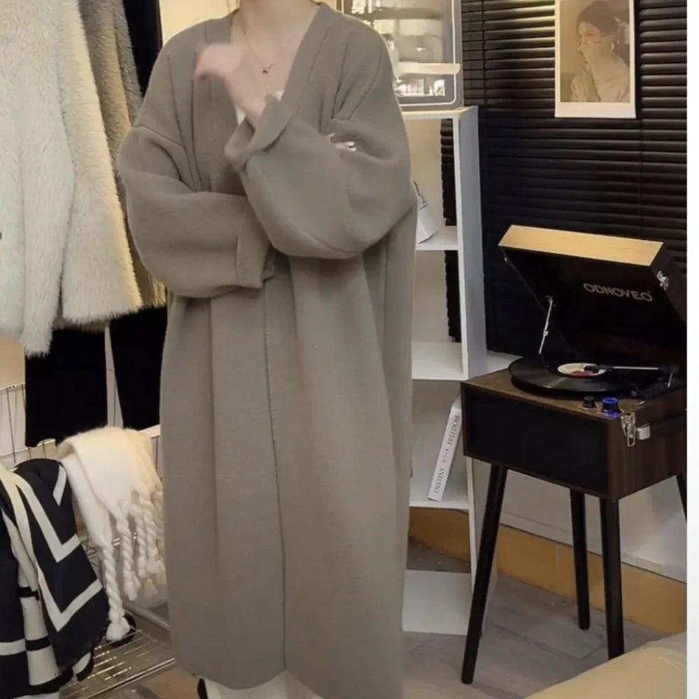 Kvinde iført beige frakke i moderne stue med pladespiller og sort-hvide dekorationer. Stilfuldt interiør, minimalistisk design, trendy mode.