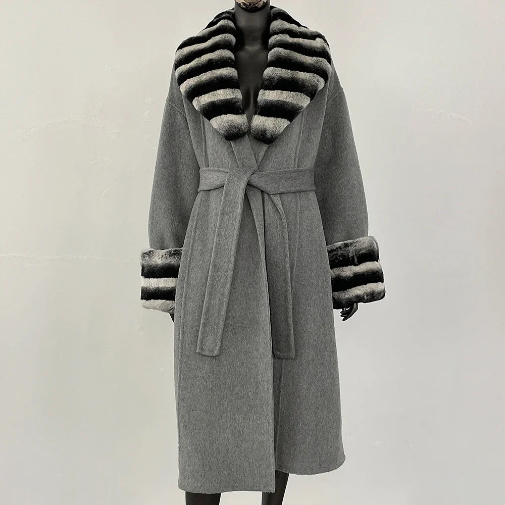 Grå frakke med bælte og sort-hvid stribet pelskrave og manchetter, elegant vintermode, luksuriøs dameovertøj, stilfuldt design.