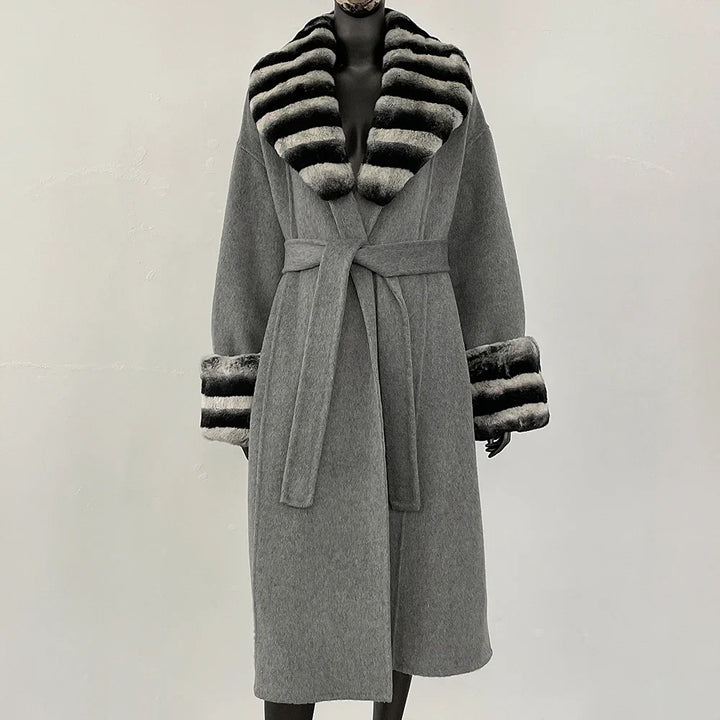 Grå frakke med bælte og sort-hvid stribet pelskrave og manchetter, elegant vintermode, luksuriøs dameovertøj, stilfuldt design.