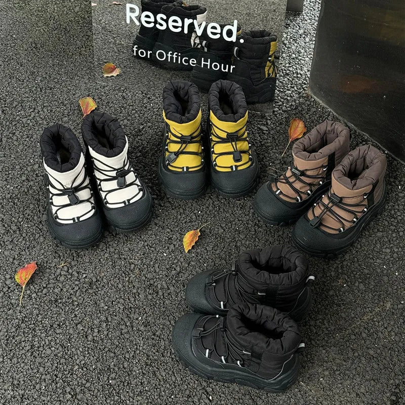 Fire par vinterstøvler i forskellige farver på grusvej, omgivet af efterårsblade. Perfekte til kolde vejrforhold og udendørsaktiviteter.