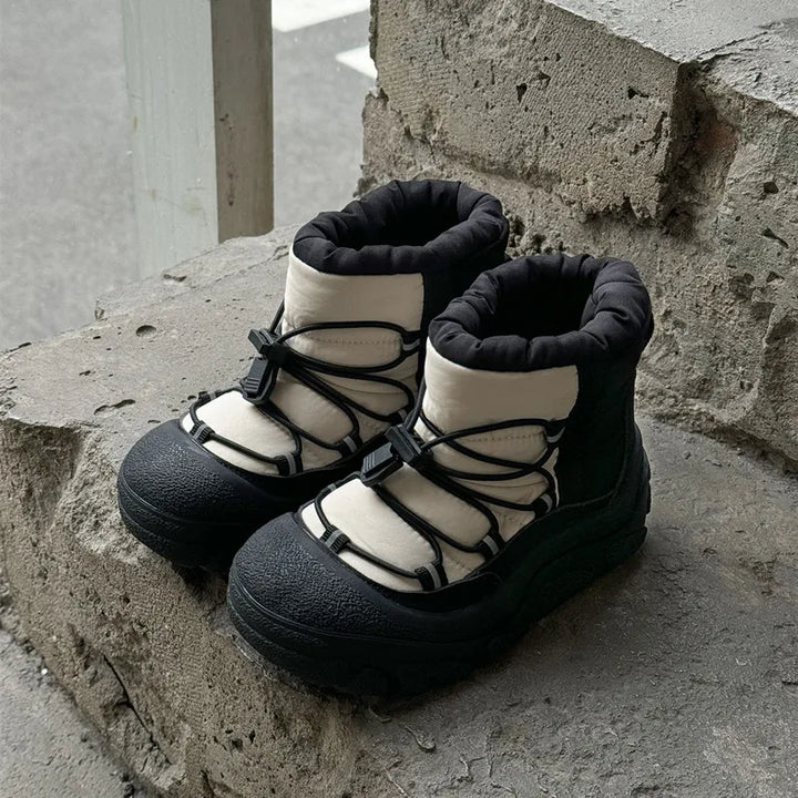 Sort-hvide vandrestøvler med snørebånd på betonoverflade. Komfortable og slidstærke sko til udendørsaktiviteter. Perfekte til vandreture og trekking.