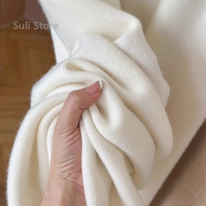 Hånd holder blødt, hvidt kashmirstof fra Suli Store. Luksuriøst, varmt materiale ideelt til vintertøj og strik. Perfekt til modeentusiaster.