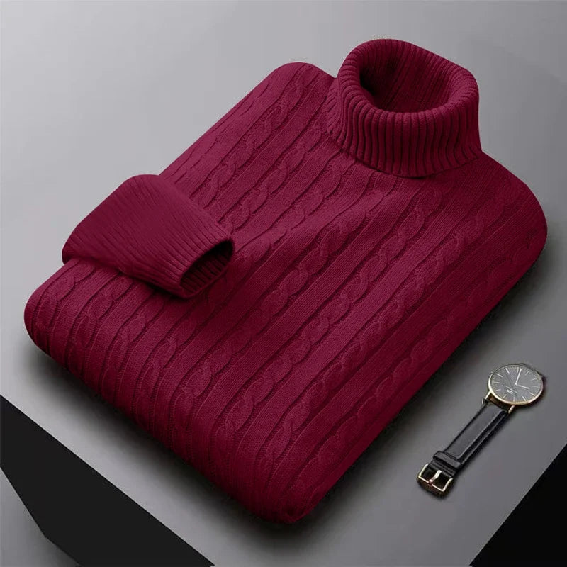 Bordeaux rullekrave sweater i kabelstrik på grå baggrund ved siden af et elegant armbåndsur. Perfekt til vintermode og stilfuldt herretøj.