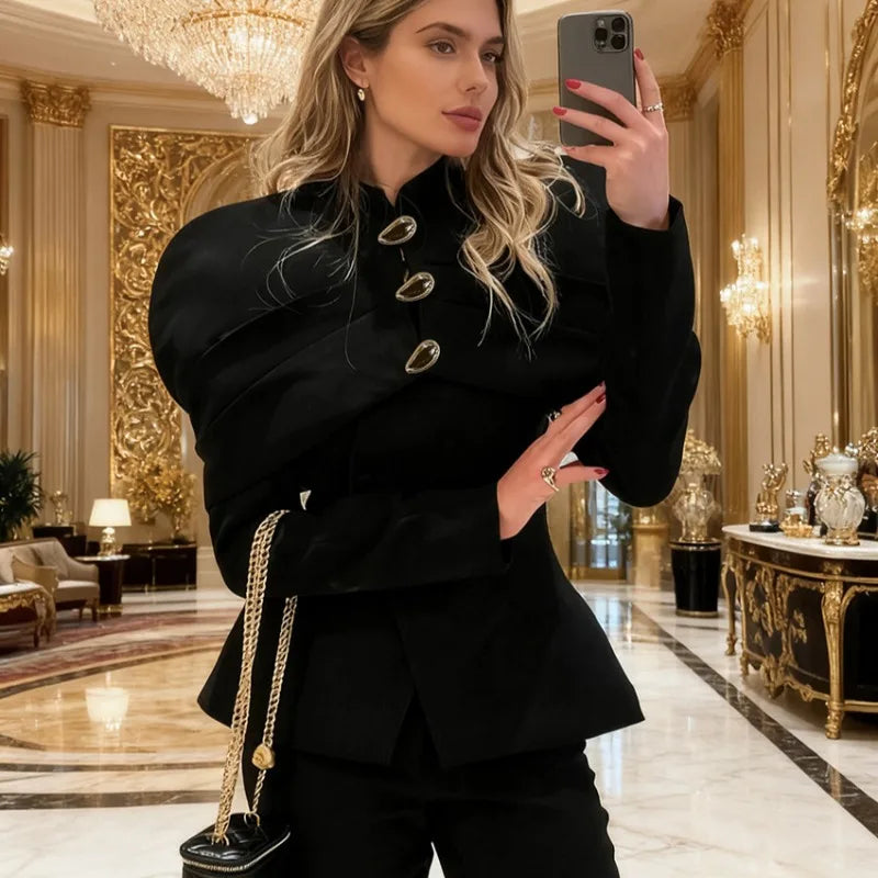 Kvinde i elegant sort jakke tager selfie i luksuriøs gylden indretning. Mode, stilfuldt tøj, selfie, luksusinteriør, moderne kvinde.