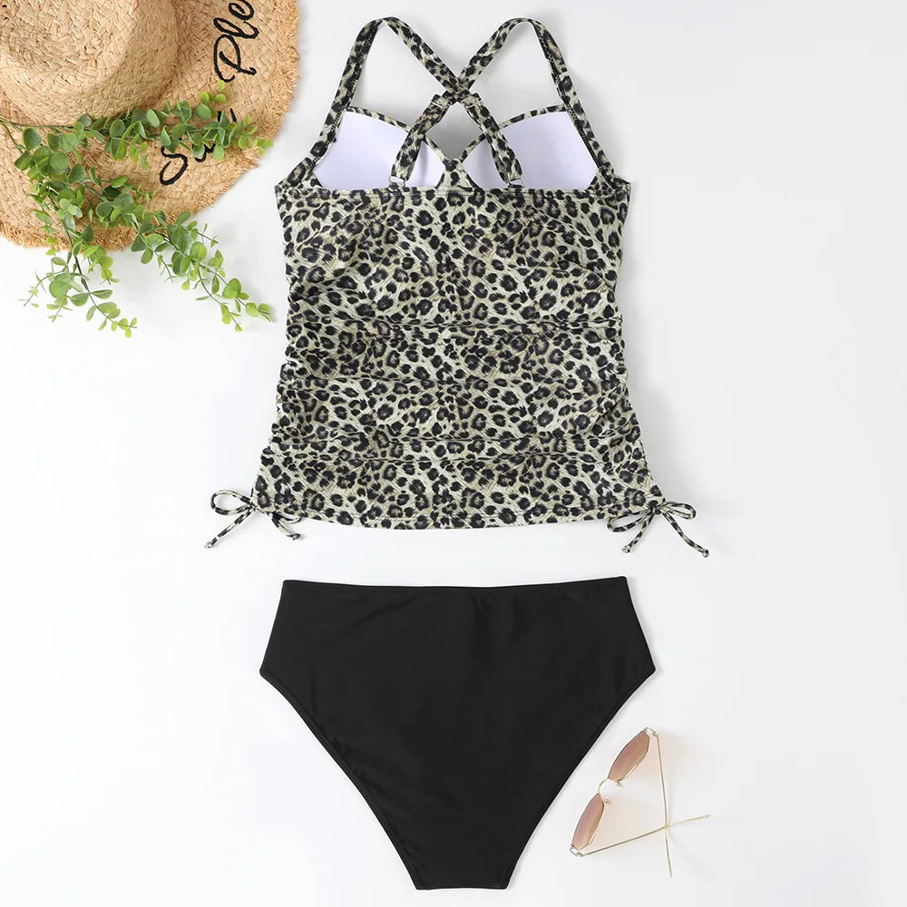 Leopardmønstret tankini med sorte bikinitrusser, solhat, solbriller og grønne blade. Perfekt til strandmode og sommerstil.