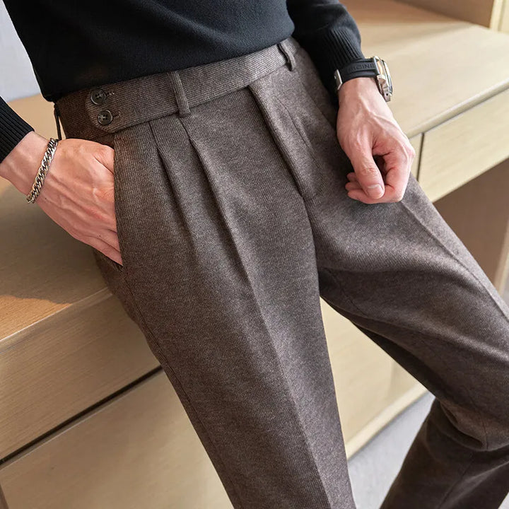 Brun herrebukser i uld med plisserede detaljer, bælteløkker og sidelommer. Elegant og stilfuldt design til moderne herremode.