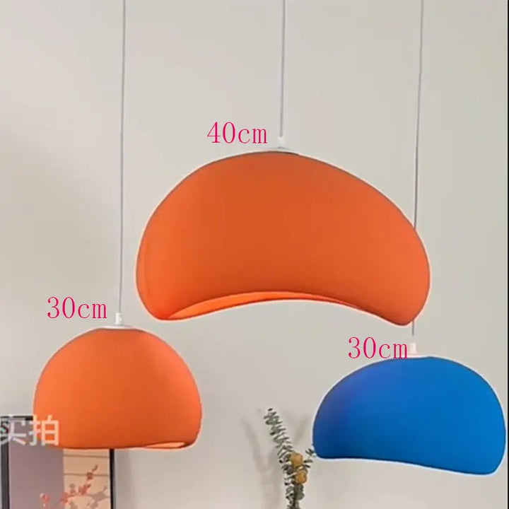 Tre moderne pendellamper i orange og blå, hængende i forskellige højder. Størrelserne er 40 cm og 30 cm. Minimalistisk design til stueindretning.