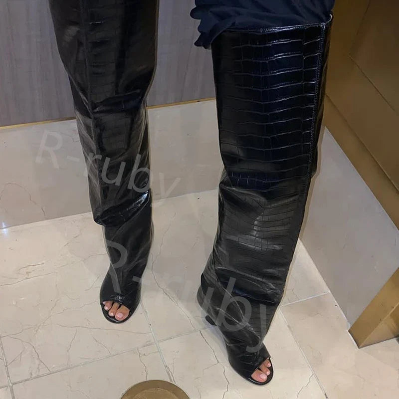 Sort krokodillelæder overknee støvler med åben tå på marmorgulv. Moderne fodtøj, luksusdesign, stilfulde støvler til modebevidste kvinder.