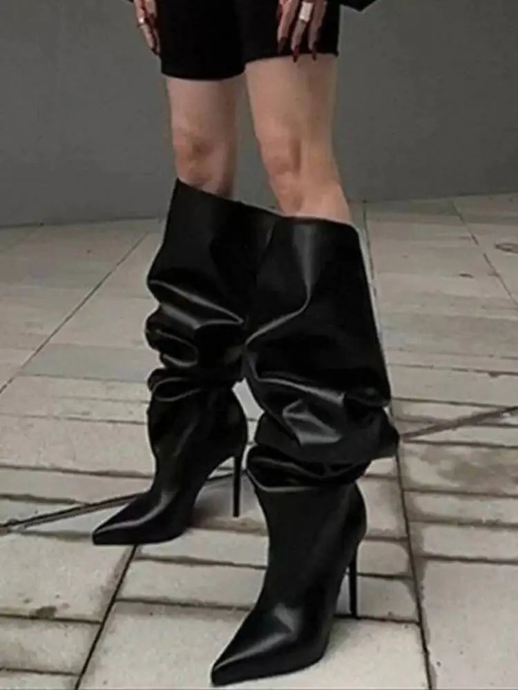 Sort læderstøvler med høj hæl og rynket skaft på flisebelagt fortov. Moderne fodtøj, stilfuldt design, modeaccessory, kvindelige ben.