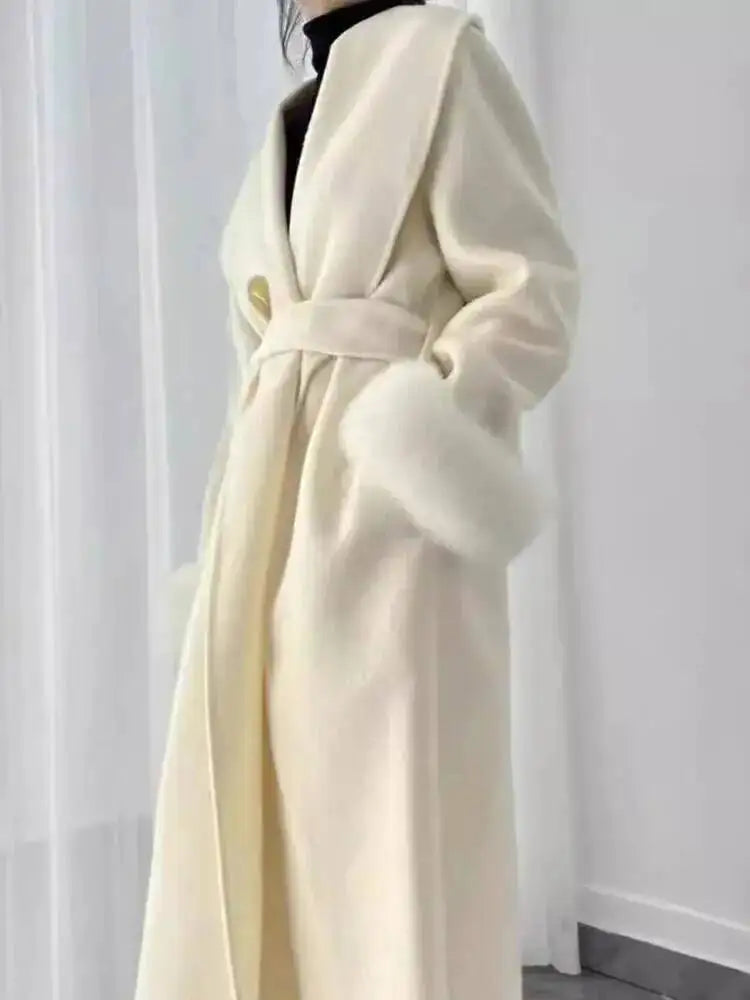 Elegant hvid frakke med bælte og pelsdetaljer, perfekt til vintermode. Stilfuldt design, ideel til kolde sæsoner. Luksuriøs og moderne beklædning.