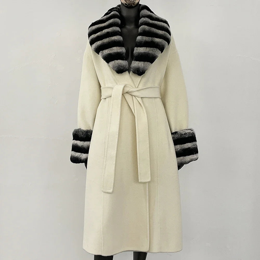 Elegant hvid frakke med sortstribede pelsdetaljer på krave og ærmer, bælte i taljen. Stilfuldt vintertøj til kvinder.