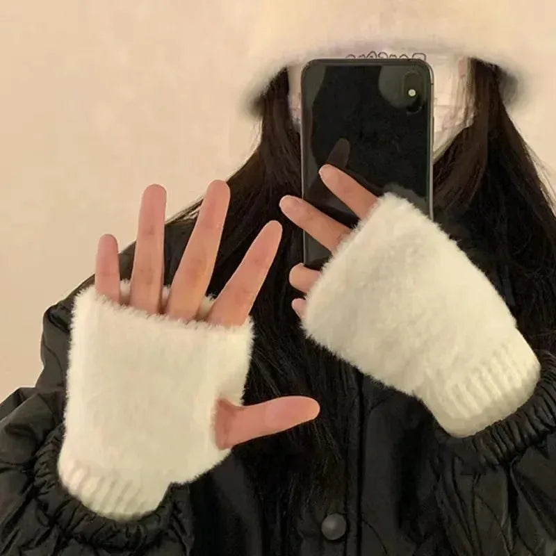 Kvinde iført hvid pelsbøllehat og matchende fingerløse handsker, tager selfie med smartphone. Vintermode, trendy tilbehør, stilfuldt look.