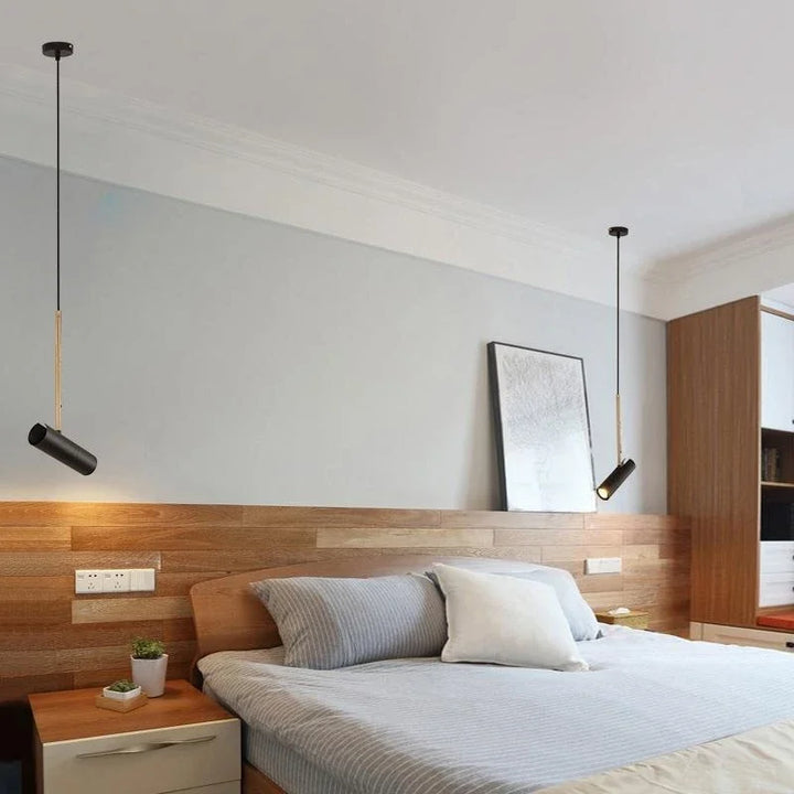 Moderne soveværelse med træpaneler, grå vægge og minimalistiske hængelamper. Dobbeltseng med stribede puder og natbord med plante.