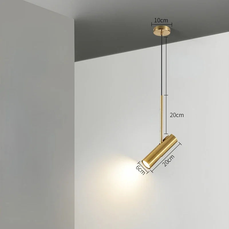 Guldfarvet cylinderformet pendellampe med mål: 10 cm loftplade, 20 cm stang, 6 cm diameter, 20 cm længde. Moderne belysning til stue eller køkken.