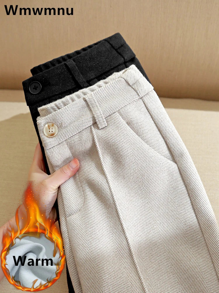 To par bukser i sort og beige med knapper, holdt i en hånd. Tekst "Warm" med flammeikon indikerer varmeegenskaber.