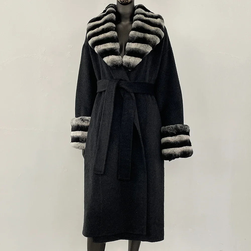 Sort frakke med bælte og stribede pelsdetaljer på krave og ærmer. Elegant vintermode, luksuriøs damefrakke, stilfuldt design.