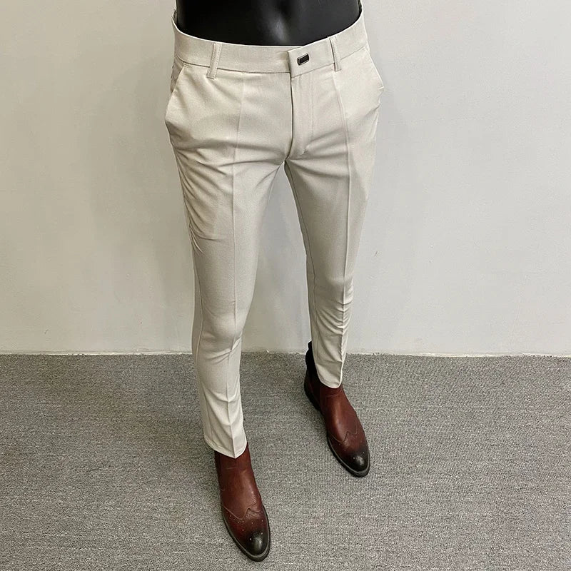 Beige herrebukser på mannequin med brune læderstøvler, moderne slim fit design, velegnet til formelle og afslappede lejligheder.