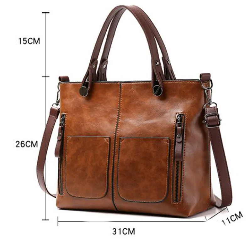 Brun læderhåndtaske med justerbar skulderrem, to forlommer og lynlåse. Mål: 31x26x11 cm. Stilfuld og praktisk til daglig brug.