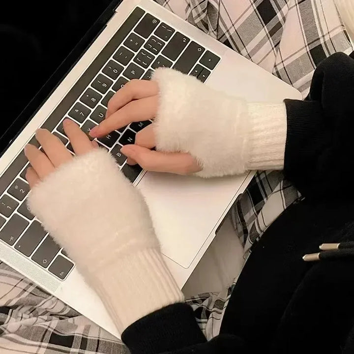 Hænder med hvide fingerløse handsker skriver på en bærbar computer. Komfortabelt tøj, plaid mønster, vintertilbehør, teknologi.