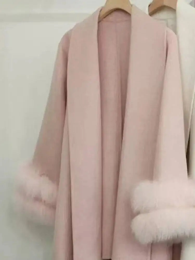 Lyserød frakke med pelsdetaljer på ærmerne, hængende på en bøjle. Elegant vinterjakke, moderigtigt design, luksuriøst tøj til kvinder.