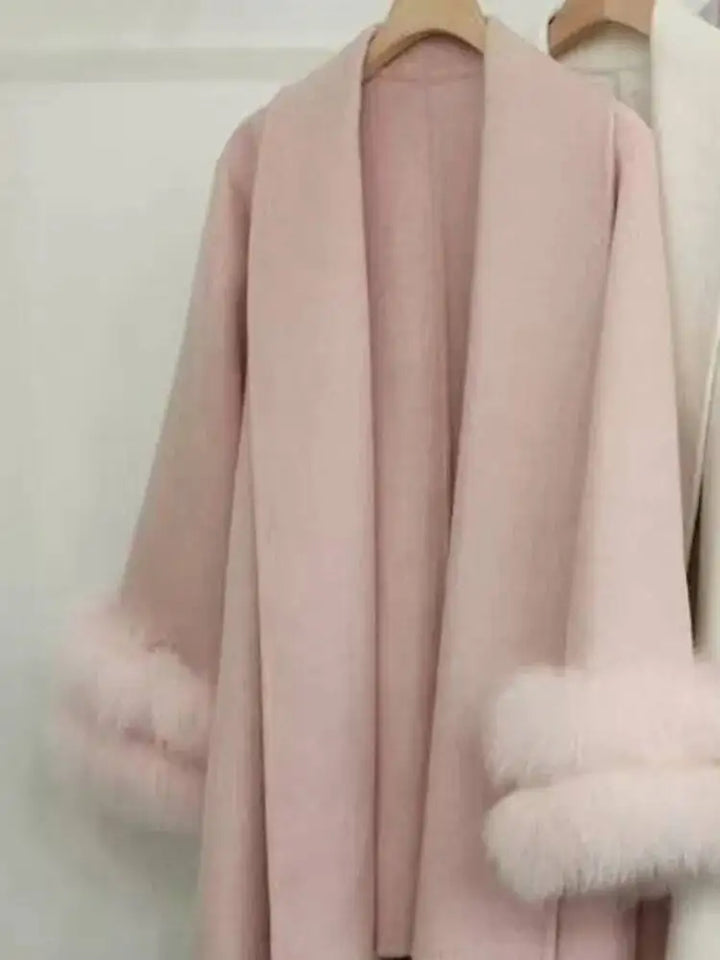 Lyserød frakke med pelsdetaljer på ærmerne, hængende på en bøjle. Elegant vinterjakke, moderigtigt design, luksuriøst tøj til kvinder.