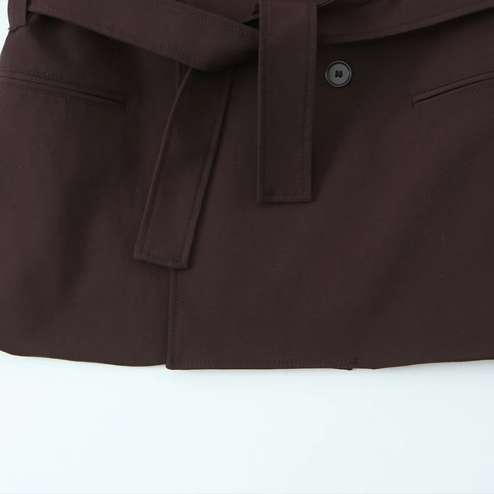 Mørkebrun trenchcoat med bælte og knapdetaljer, elegant design, velegnet til efterårsmode. Perfekt til stilfulde og moderne outfits.